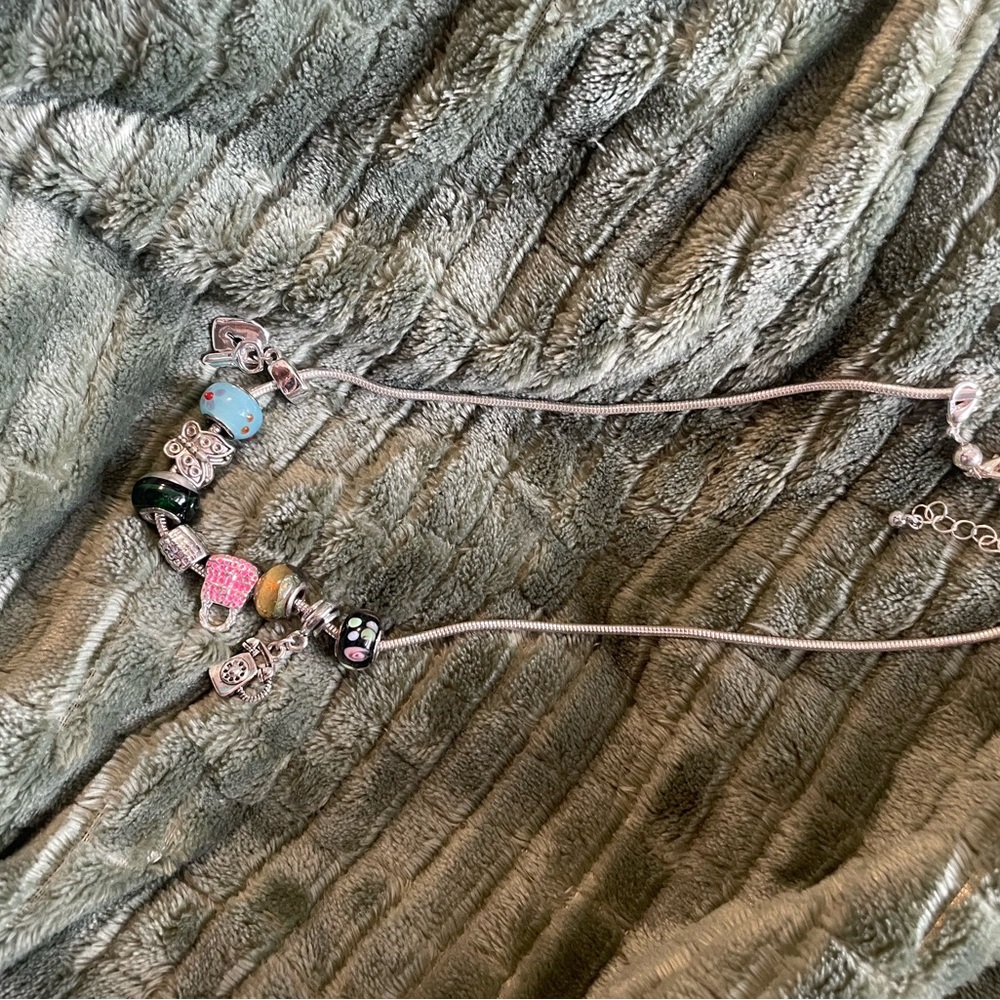 Charm necklace with heart and key, purse, butterfly, and telephone.